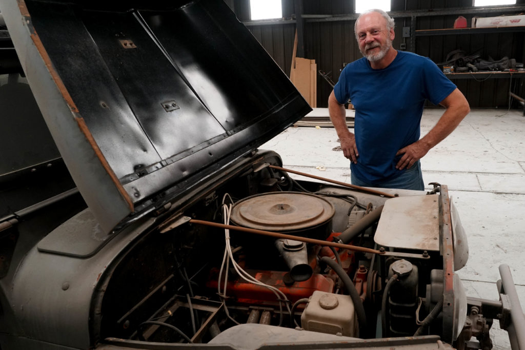 Man standing by a Jeep with the hood raised