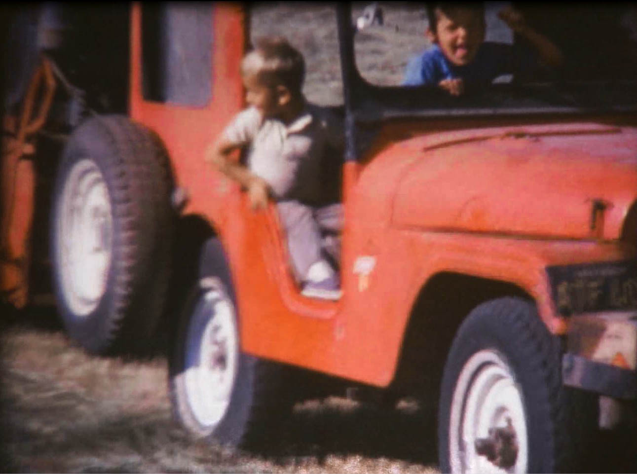 Two boys riding in a red Jeep
