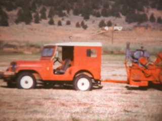 Red Jeep pulling a hay baler