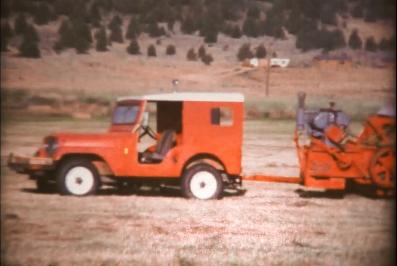 Red Jeep pulling a hay baler