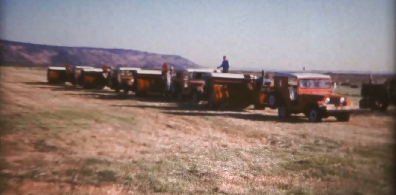 Jeeps towing hay balers in a row