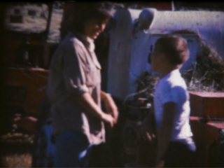 A women and her son next to a haybaler