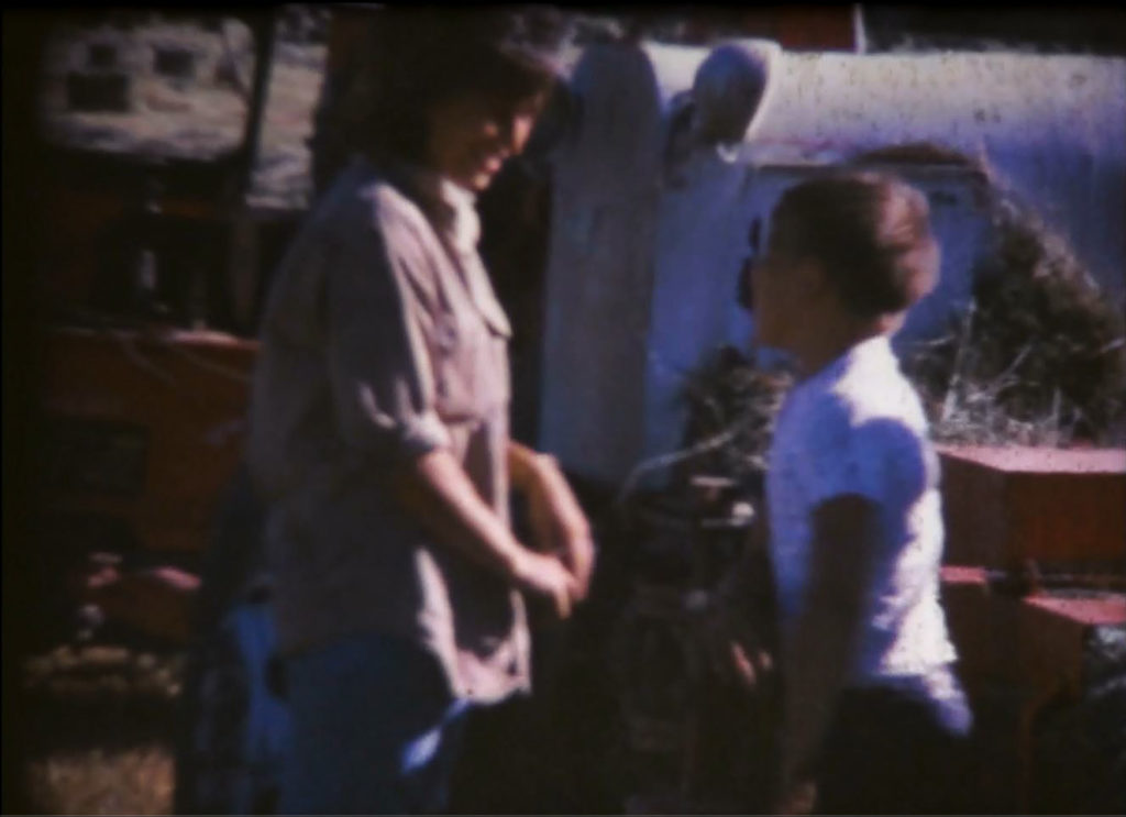 A women and her son next to a haybaler