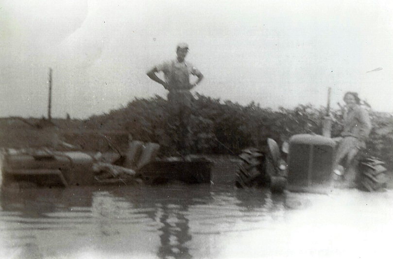 Francie Marvin standing on the Jeep in a flooded barnyard